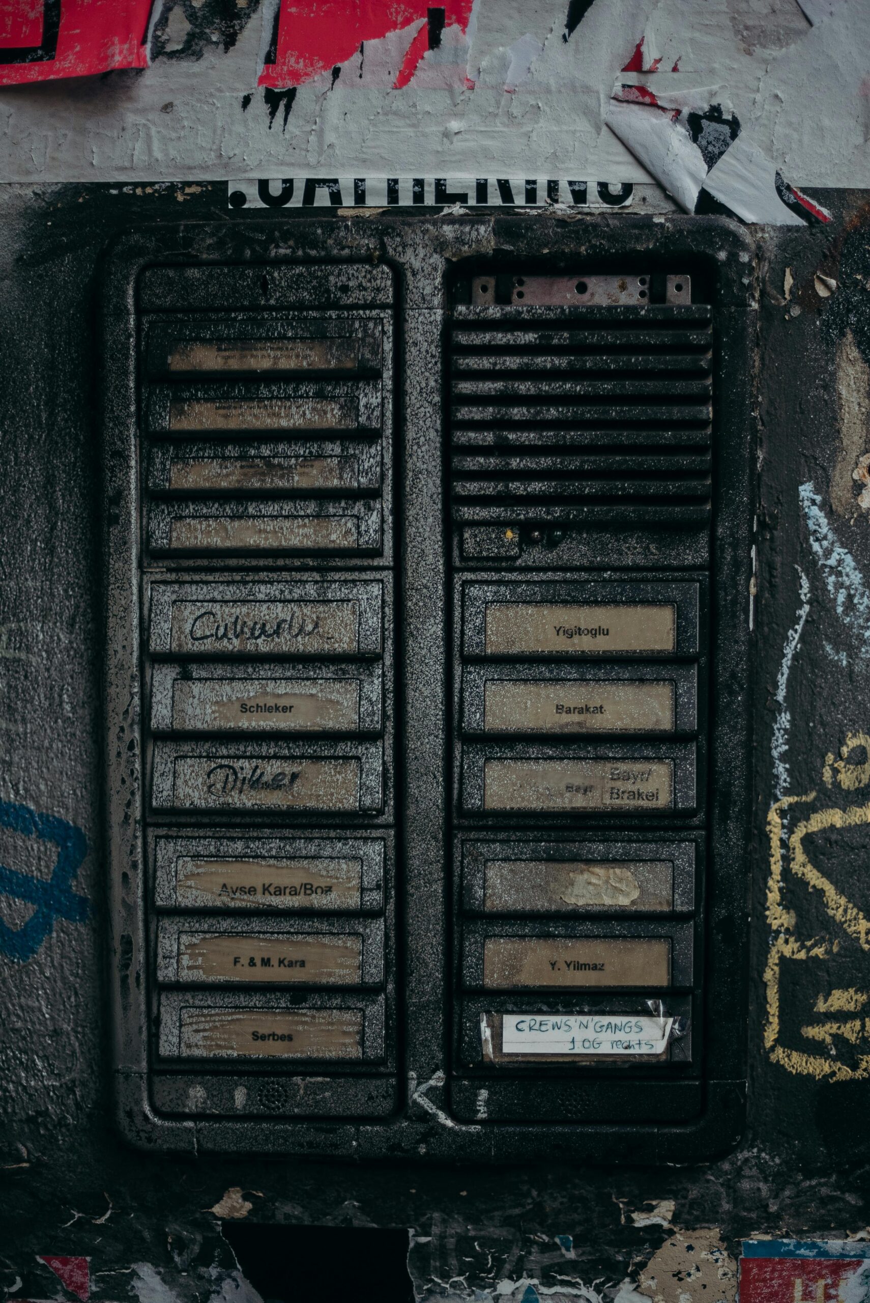 Close-up of a vintage intercom panel with graffiti in an urban setting, showcasing textured details.